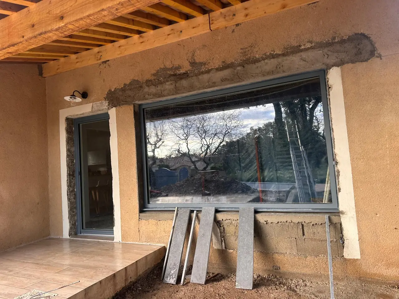 Grande baie posée dans un mur ouvert, sous une avancée de toit en bois