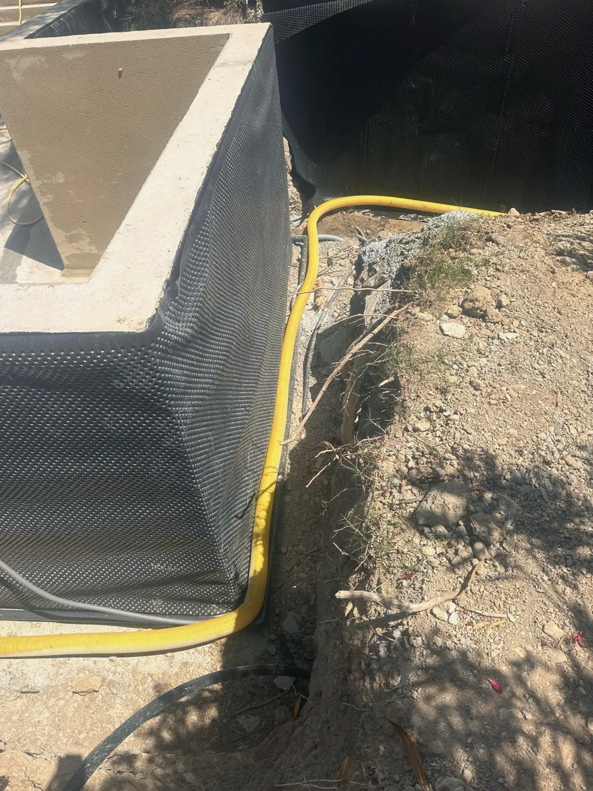 Angle d’un ouvrage enterré : nappe à excroissances et drain jaune, terre de remblai à côté