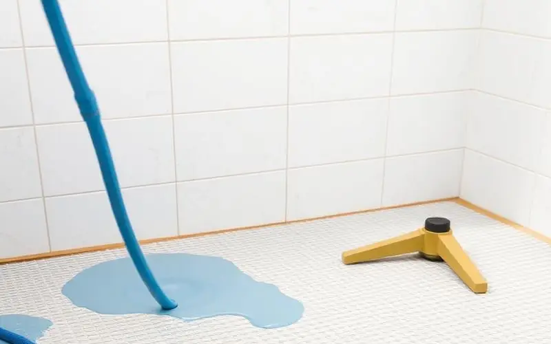 Sol d’une future douche en cours d’étanchéité, natte blanche posée au pied d’une faïence murale