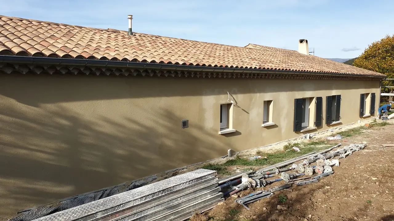 Maison de plain-pied crépie, toit en tuiles, abords encore en chantier