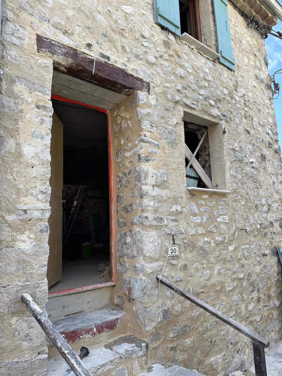 Façade en pierre : porte sous un linteau en bois, fenêtre à côté