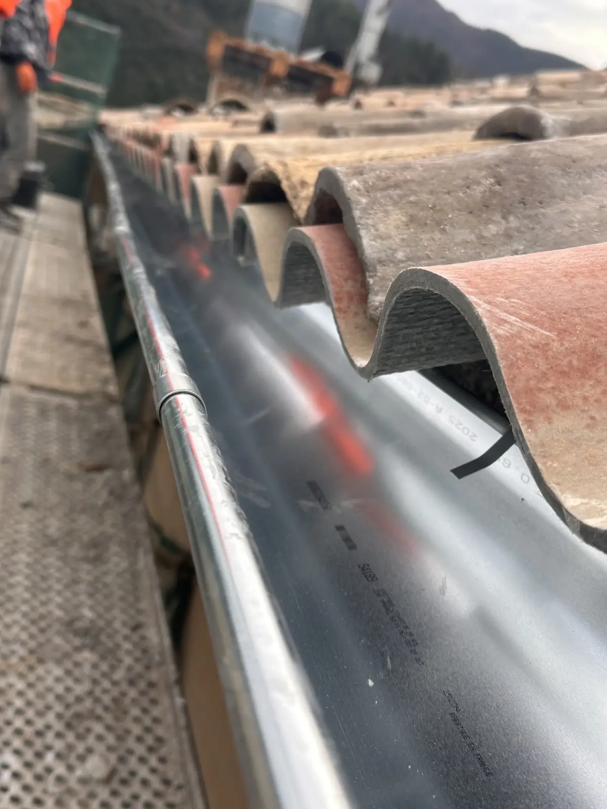Gouttière en zinc sous les tuiles de rive, vue en enfilade depuis l'échafaudage