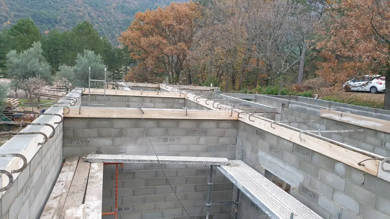 Soubassement en blocs béton, cases du vide sanitaire, arbres d’automne au fond